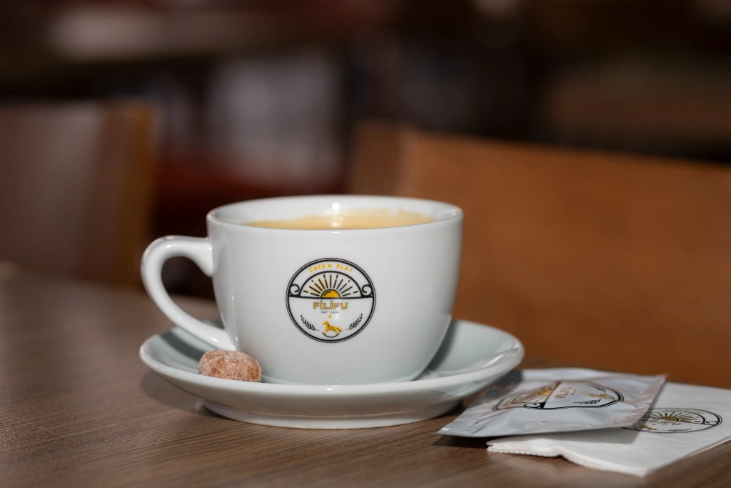 A Filifu Cafe-branded coffee cup placed elegantly on the table.