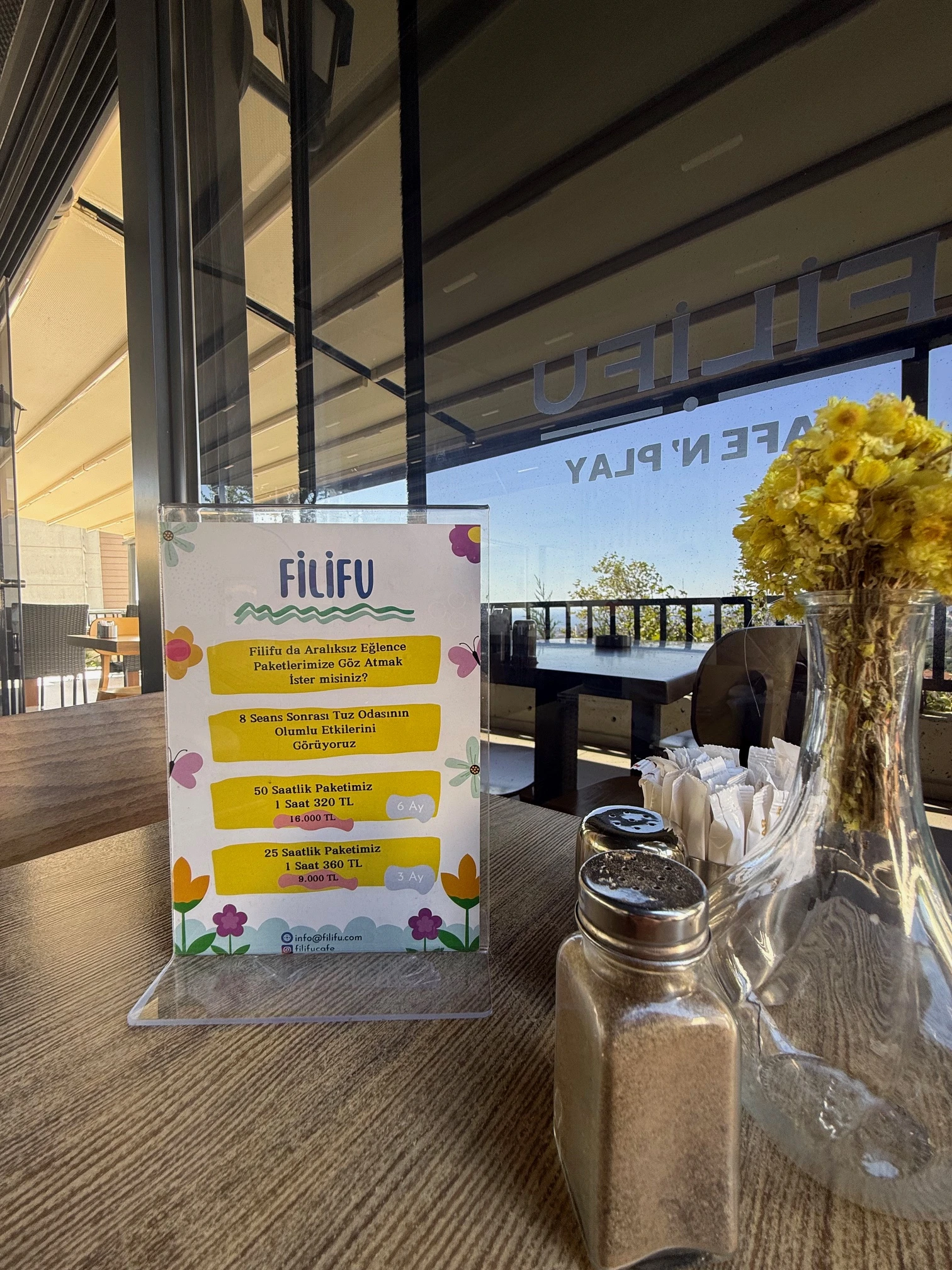 2025 Filifu Cafe N' Play fiyat listesi, 1 saat oyun alanı 450 TL, her ek yarım saat 100 TL, 25 saat abonelik 9.000 TL ve 50 saat abonelik 16.000 TL, renkli çocuk oyun alanı ve tuz odası terapisi alanıyla.