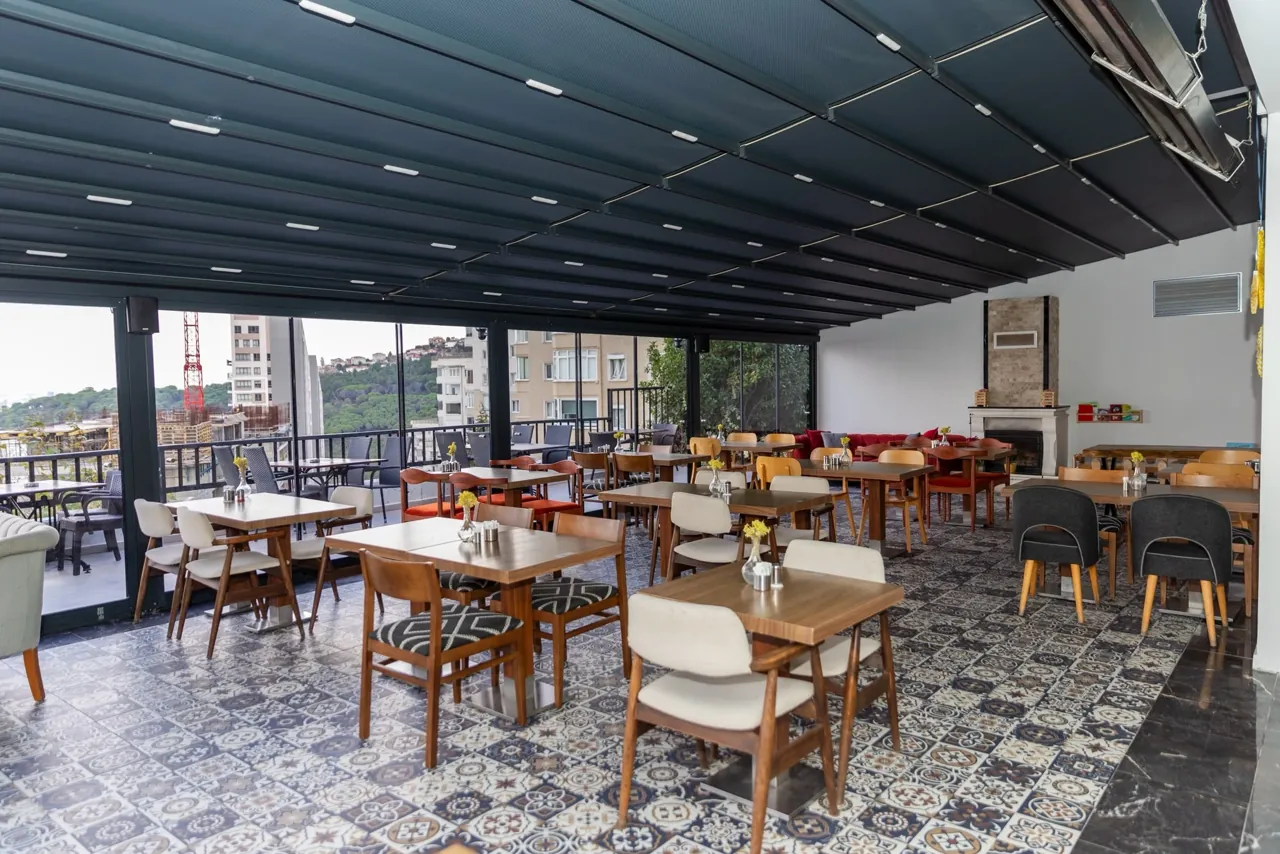Wooden tables and mixed chairs beneath the dark ceiling in the Filifu café area