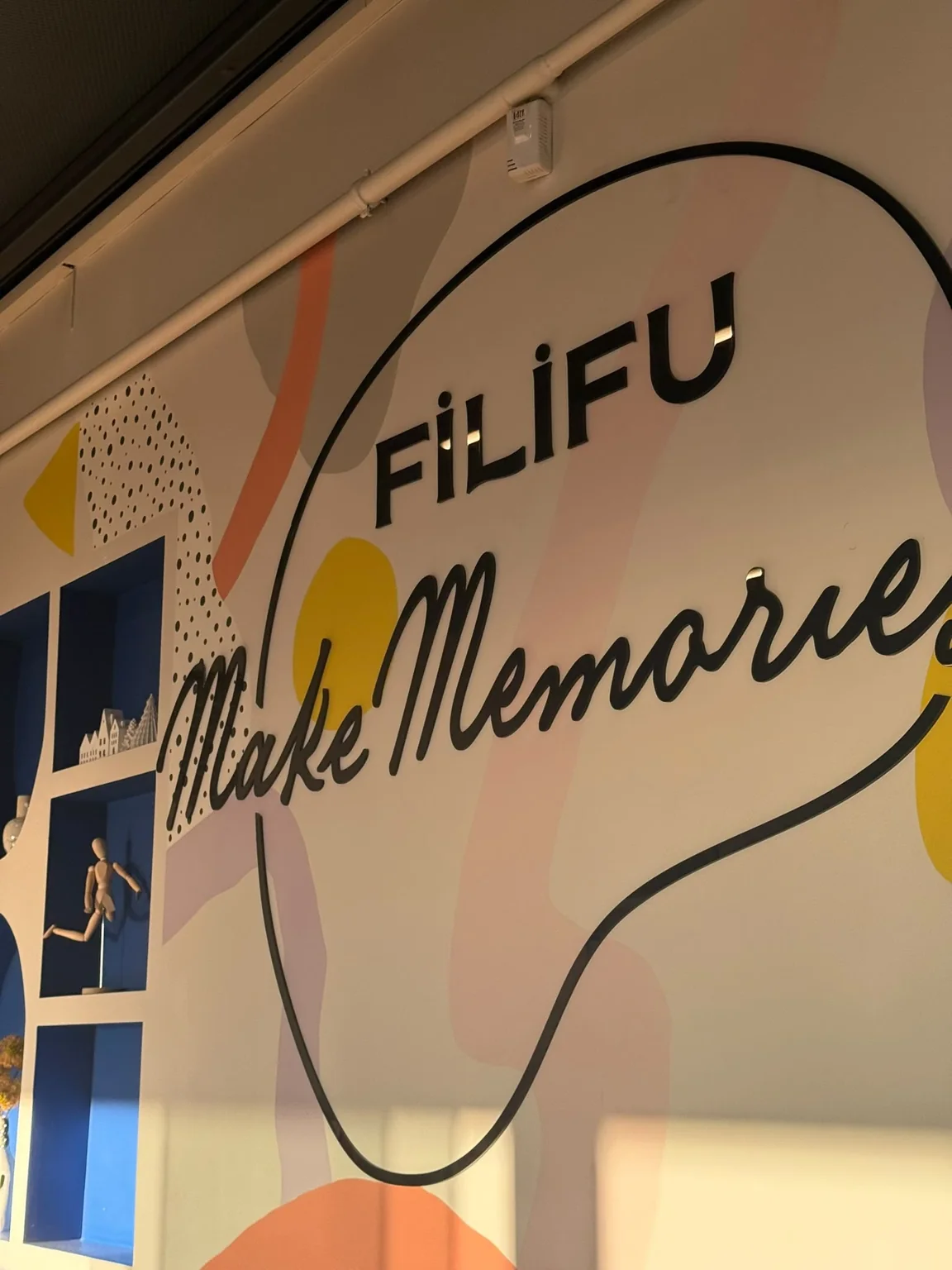 Inscription Filifu Make Memories sur un mur décoré de couleurs pastel