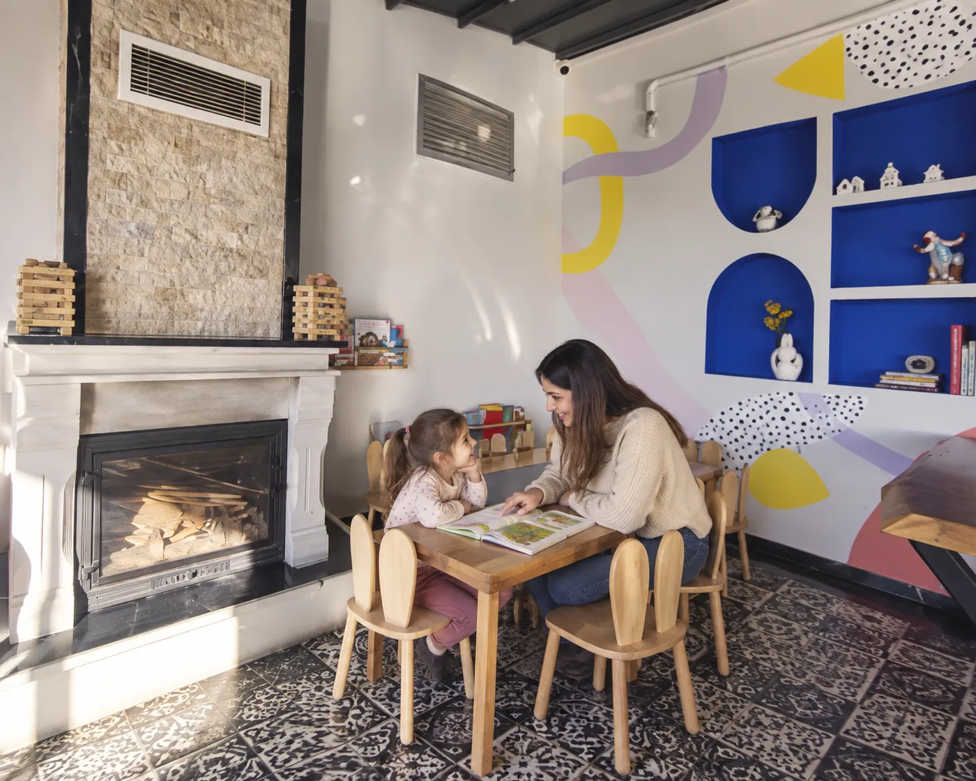 Un genitore e un bambino leggono insieme un libro illustrato sulla famiglia in un ambiente ispirato a Filifu Cafe