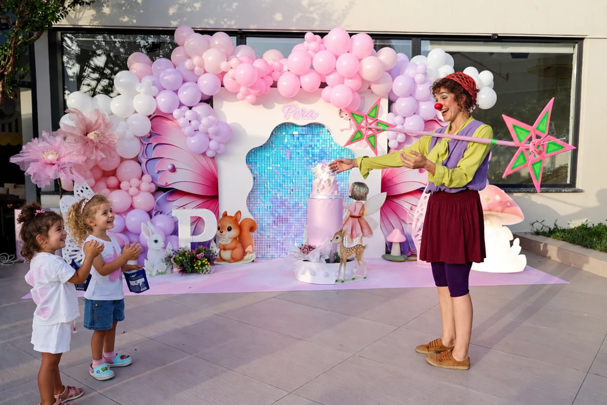 Filifu’nun açık alanında pastel balonlarla süslü doğum günü dekoru önünde çocuklara gösteri yapan animatör