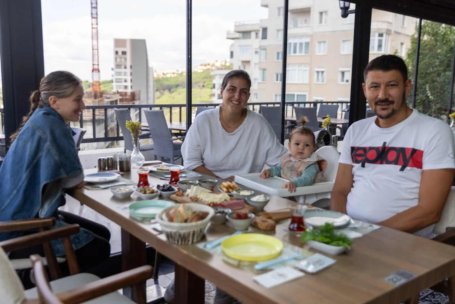 Des adultes et deux enfants autour d’une table de petit-déjeuner près de grandes fenêtres