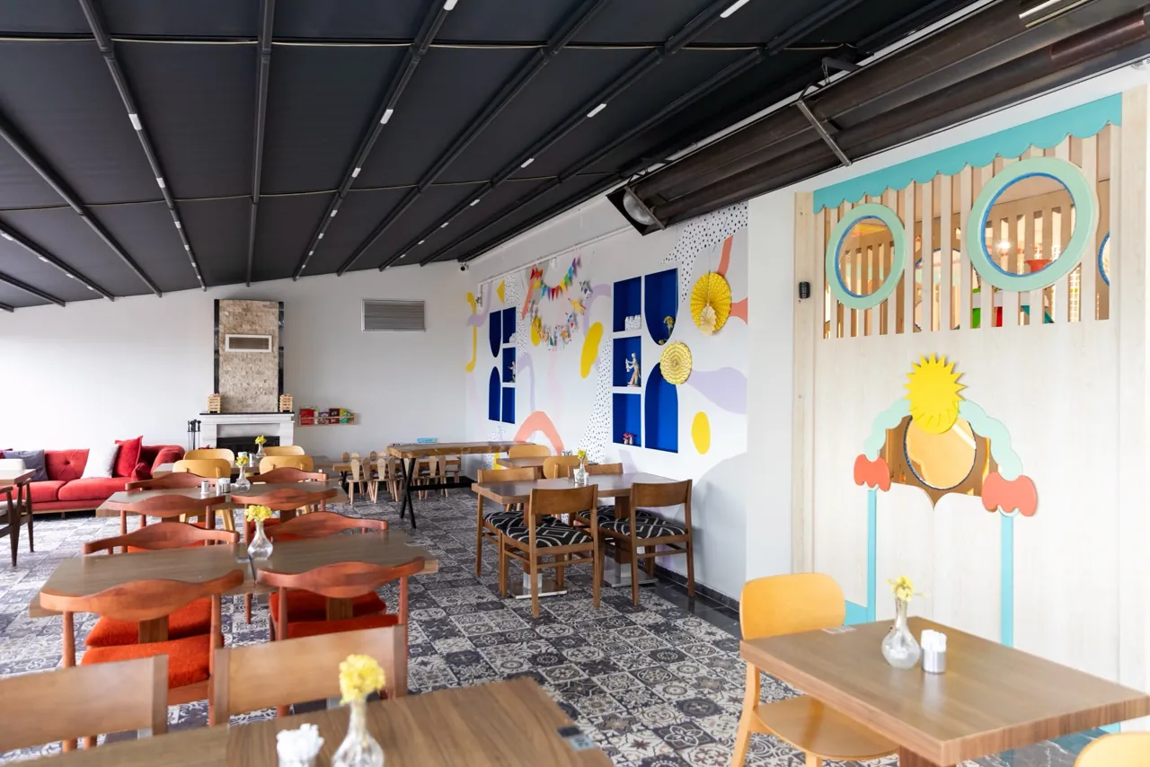 Holztische und Stühle vor einer farbig gestalteten Wand im Filifu Cafe