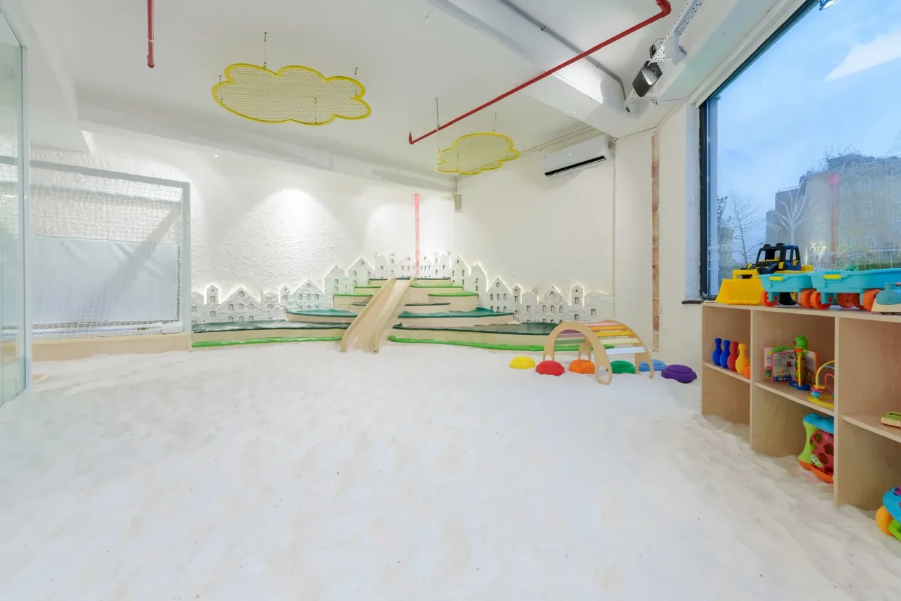 White floor, wooden slide, green-edged steps and colourful play arch in the Filifu salt room
